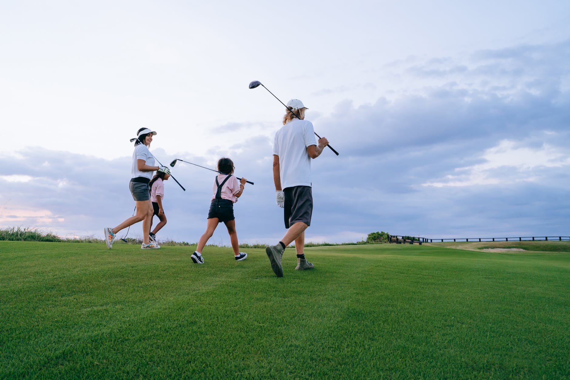 family carrying golf clubs while walking